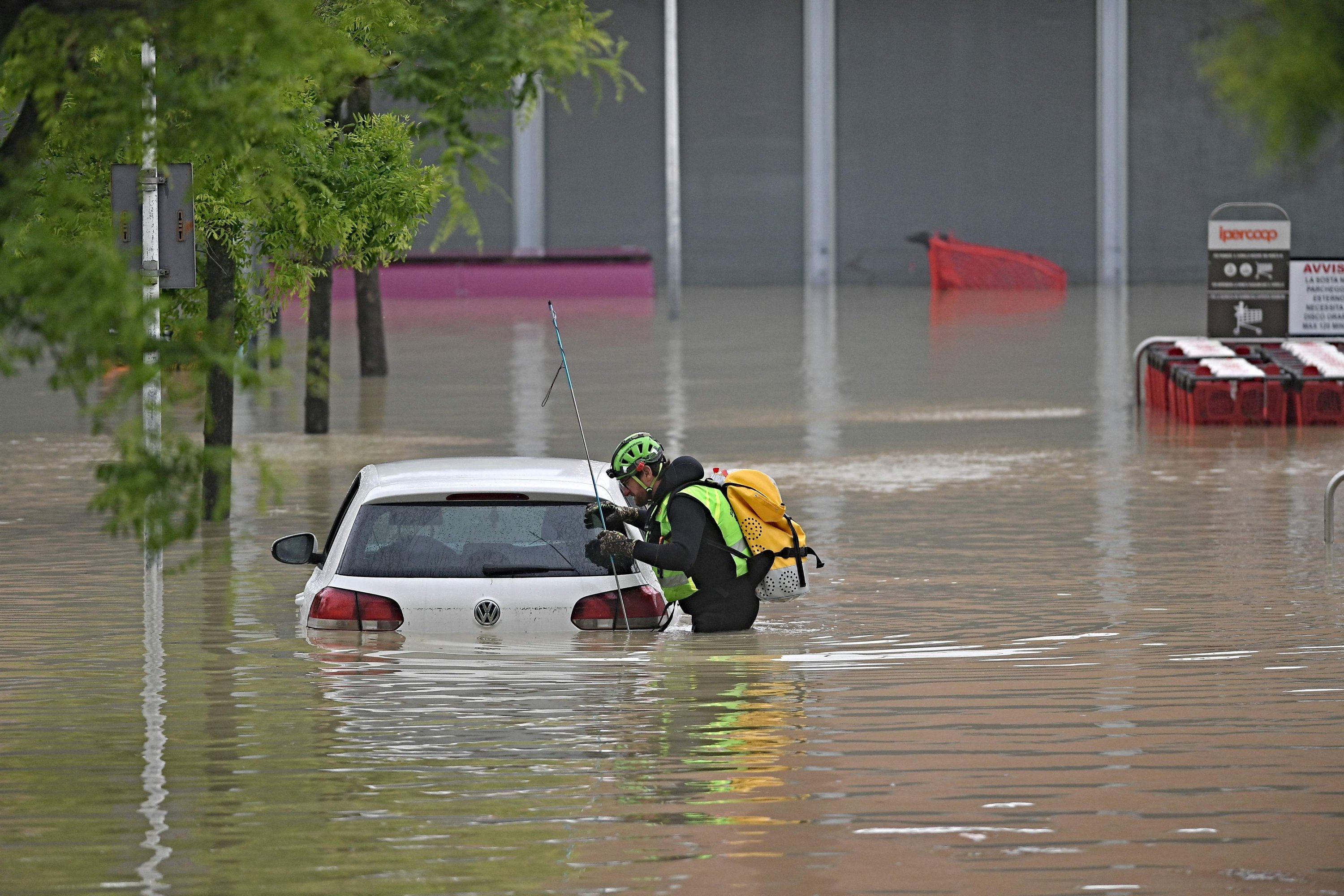 Seorang penyelamat alpine speleologi melihat ke dalam mobil untuk mencari orang hilang di dekat supermarket di daerah banjir, Cesena, Italia, 17 Mei 2023. (AFP Photo)
