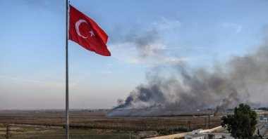 Smoke rises from the Syrian town of Tal Abyad, in a picture taken from the Turkish side of the border where the Turkish flag is seen near Akçakale, Oct. 10, 2019. (AFP Photo)
