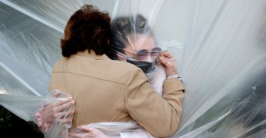 Olivia Grant (R) hugs her grandmother, Mary Grace Sileo through a plastic drop cloth in Wantagh, New York, U.S., May 24, 2020. (Getty Images)