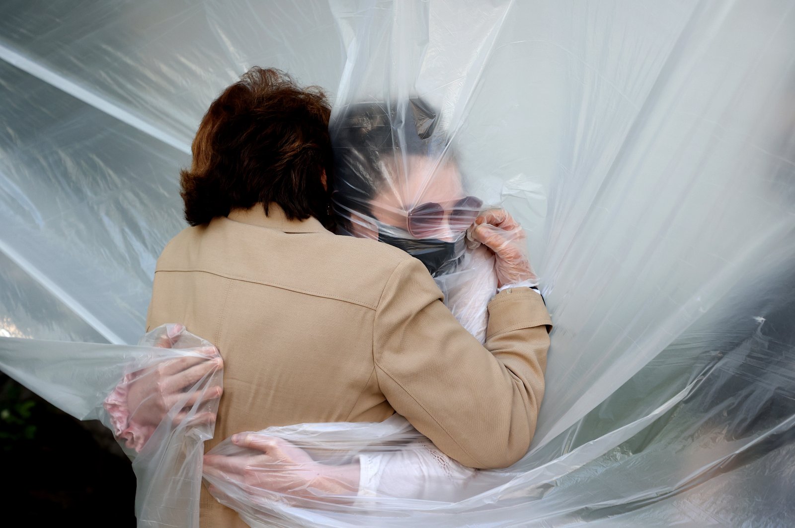 Olivia Grant (R) hugs her grandmother, Mary Grace Sileo through a plastic drop cloth in Wantagh, New York, U.S., May 24, 2020. (Getty Images)