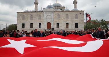 Supporters of President Recep Tayyip Erdoğan hold a large Turkish flag at an election campaign point, ahead of the May 28 runoff vote, in Istanbul, Türkiye, May 20, 2023. (Reuters Photo)