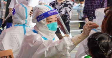A medical worker wearing medical protective clothing and a face mask takes a sample from a patient for COVID-19 tests, in Changzhou, China, May 21, 2022. (Getty Images Photo)