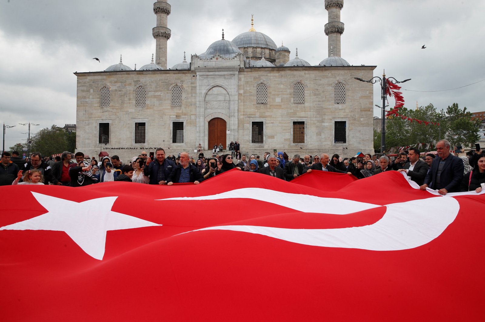 Supporters of President Recep Tayyip Erdoğan hold a large Turkish flag at an election campaign point, ahead of the May 28 runoff vote, in Istanbul, Türkiye, May 20, 2023. (Reuters Photo)