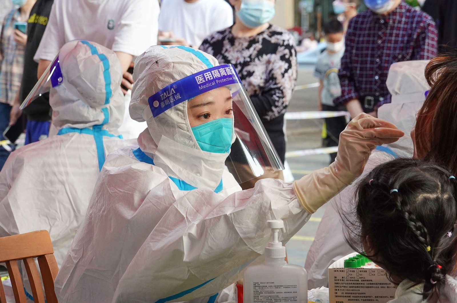 A medical worker wearing medical protective clothing and a face mask takes a sample from a patient for COVID-19 tests, in Changzhou, China, May 21, 2022. (Getty Images Photo)