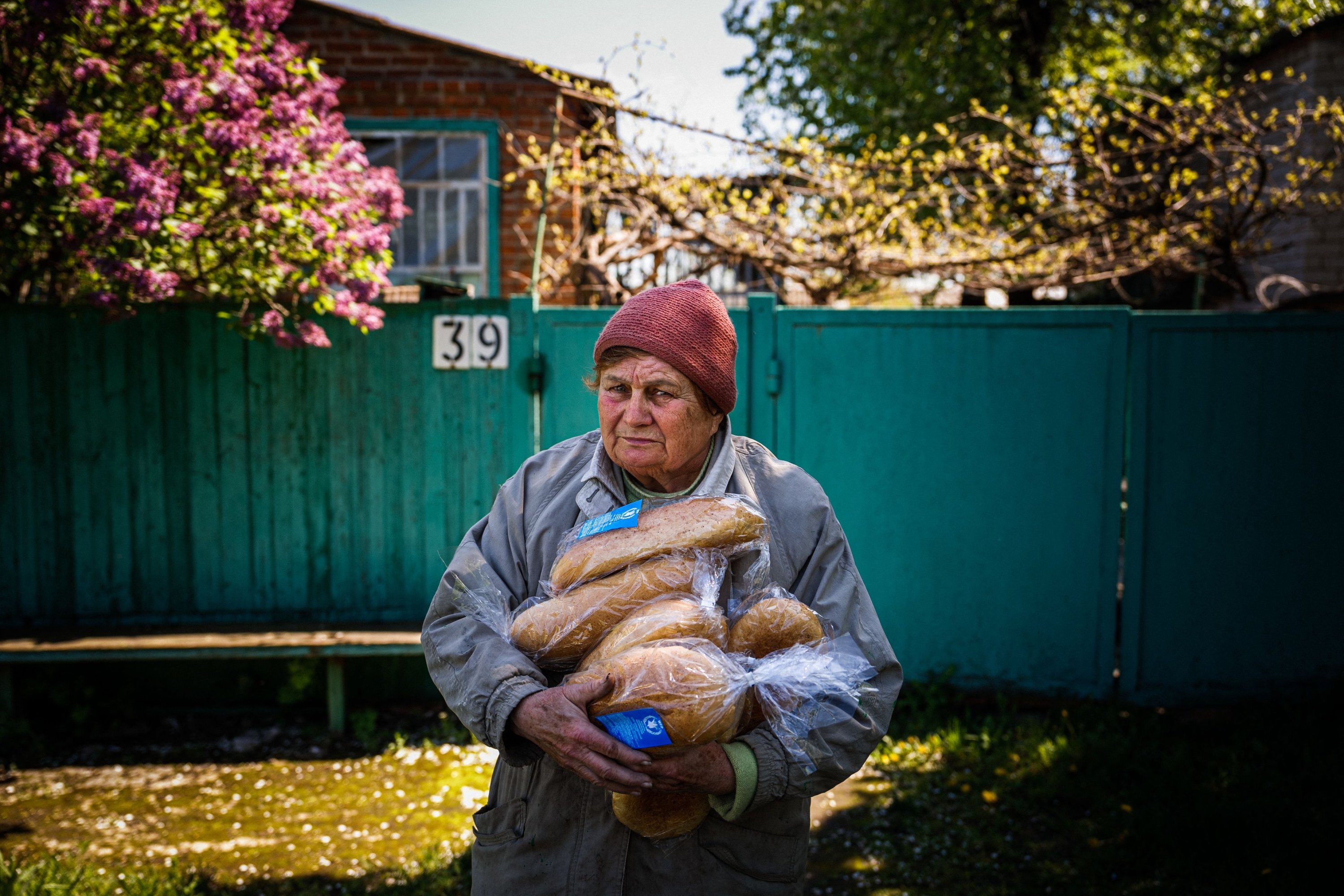 Seorang perempuan memegang roti dari bantuan kemanusiaan di depan rumahnya di Siversk, Ukraina, 2 Mei 2023. (Foto AFP)