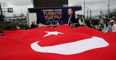 Supporters of President Recep Tayyip Erdoğan hold a large Turkish flag at an election campaign point, ahead of the May 28 runoff vote, in Istanbul, Türkiye, May 20, 2023. (Reuters Photo)