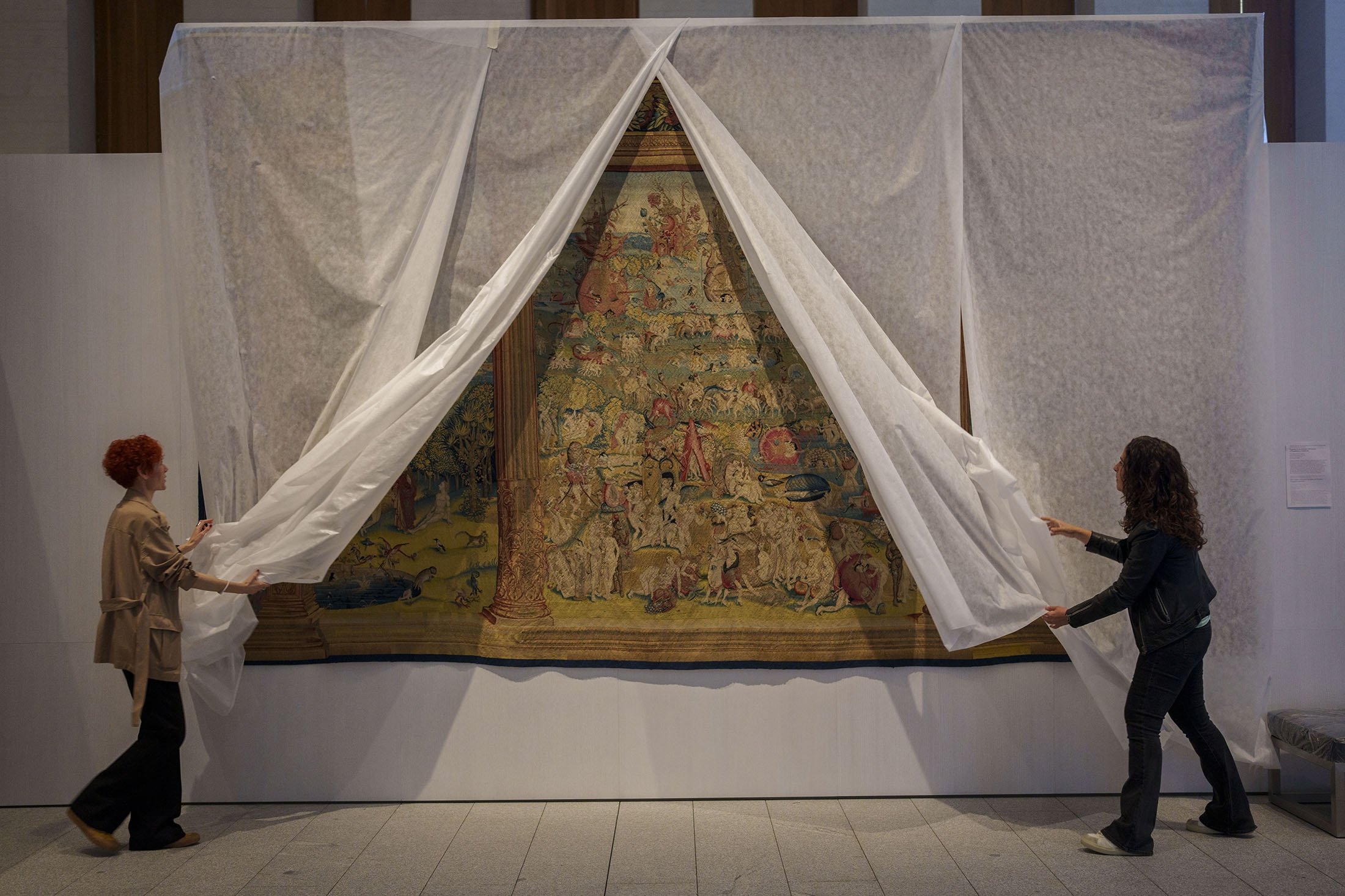 Staff members of the museum unveil a tapestry called 