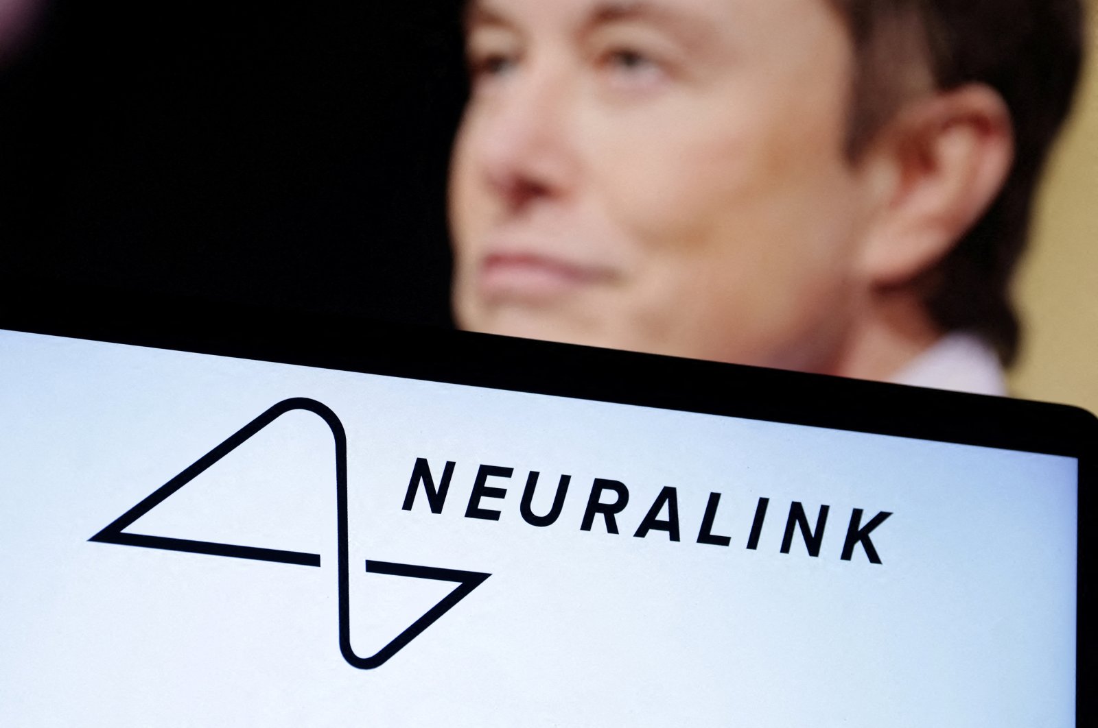 Neuralink logo and Elon Musk photo are seen in this illustration taken, Dec.19, 2022. (Reuters Photo)