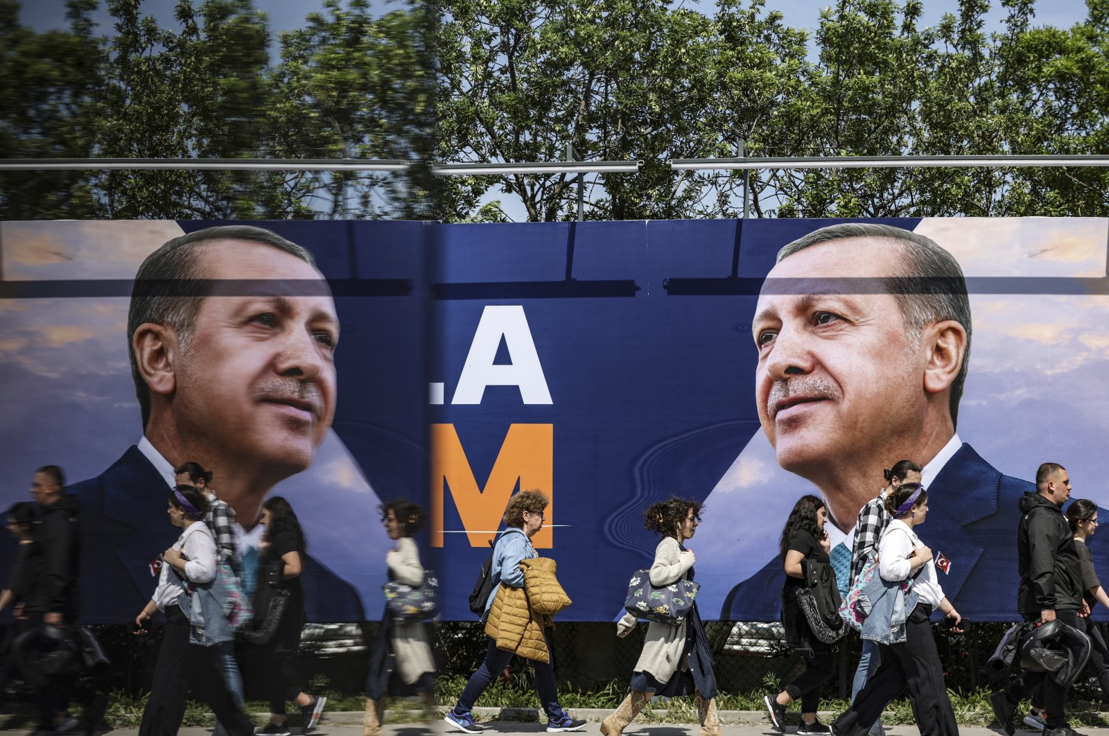 People walk in front of an election campaign poster of President Recep Tayyip Erdoğan, in Istanbul, Türkiye, May 22, 2023. (EPA Photo)