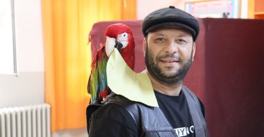 A man lets a parrot on his shoulder carry his ballot, in Denizli, Türkiye, May 28, 2023. (AA Photo)