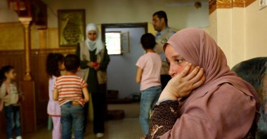 A Palestinian woman sits at her house, as a psychiatrists performs an activity with children, in Deir al-Balah, central Gaza Strip, May 16, 2023. (Reuters Photo)