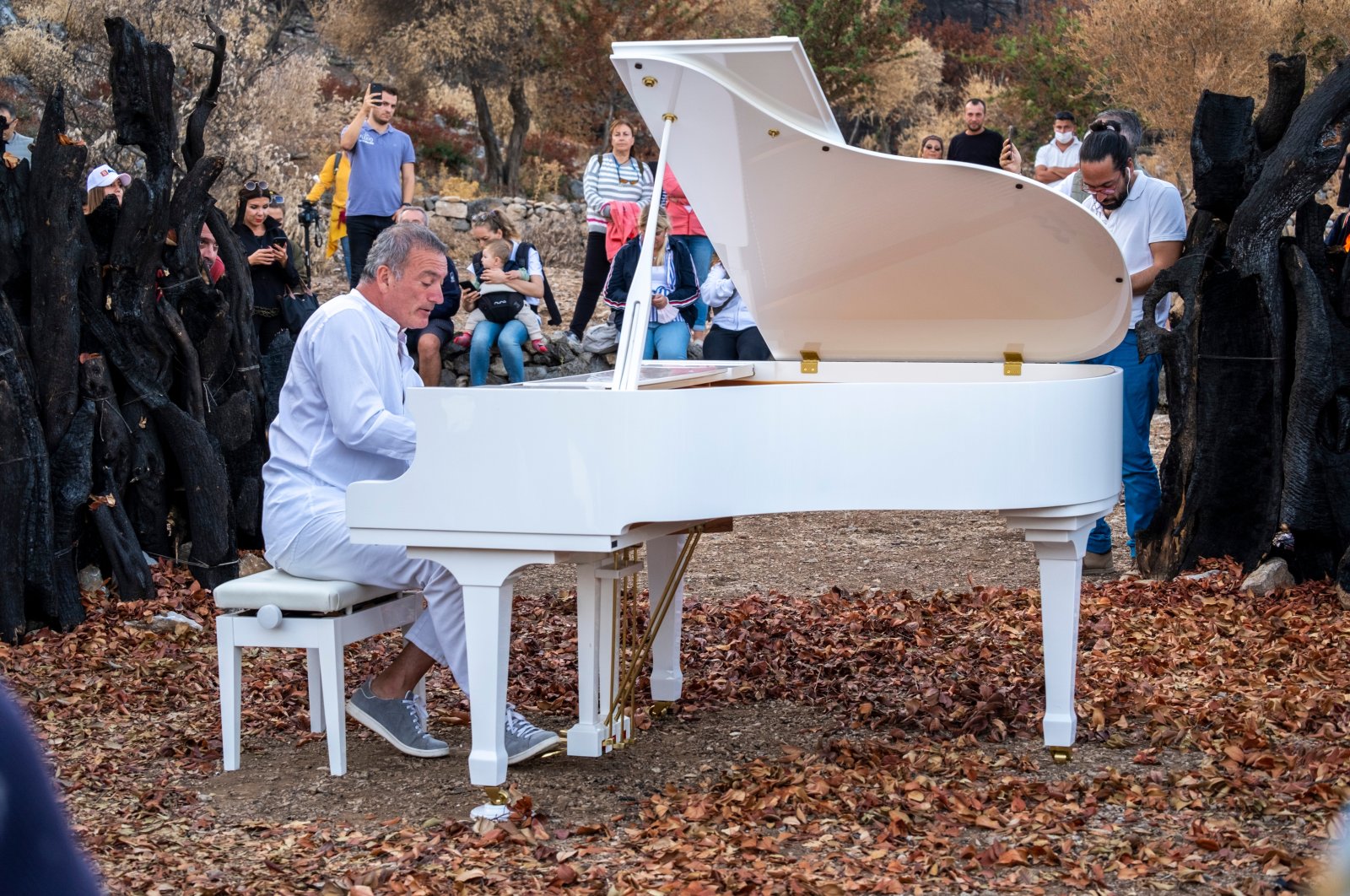 Pianist, Kerem Gorsev playing live open air on a white piano at "The Bodrum Cup" sailing festival for awareness of forest fires, Bodrum, Muğla, Türkiye, Oct. 21, 2021. (Shutterstock Photo)