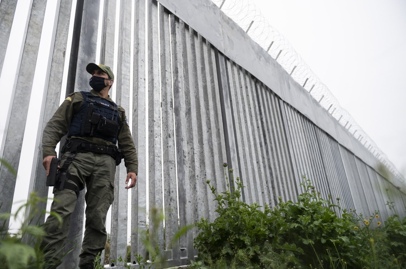 A police officer patrols alongside a steel wall at Evros River, near the village of Poros, Greece, May 21, 2021. (AP Photo)