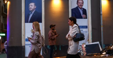 People walk in front of an election campaign poster of Turkish President Recep Tayyip Erdogan, in Istanbul, Turkey, 22 May 2023. (EPA/SEDAT SUNA)
