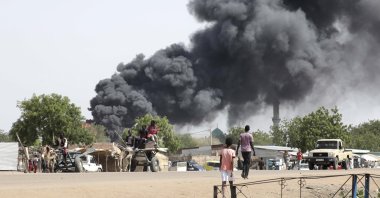 People drive as smoke rises from a fire at a market in the Upper Nile State town of Renk, South Sudan, May 13, 2023. (EPA Photo)