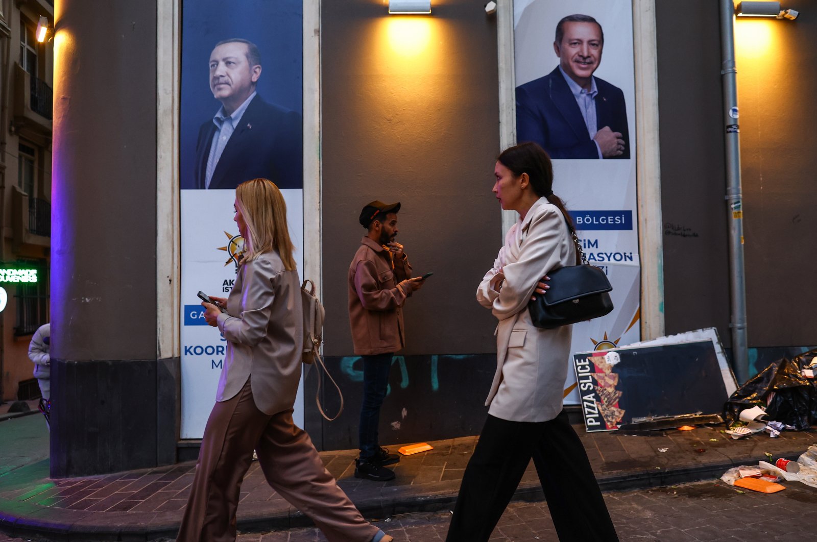 People walk in front of an election campaign poster of Turkish President Recep Tayyip Erdogan, in Istanbul, Turkey, 22 May 2023. (EPA/SEDAT SUNA)