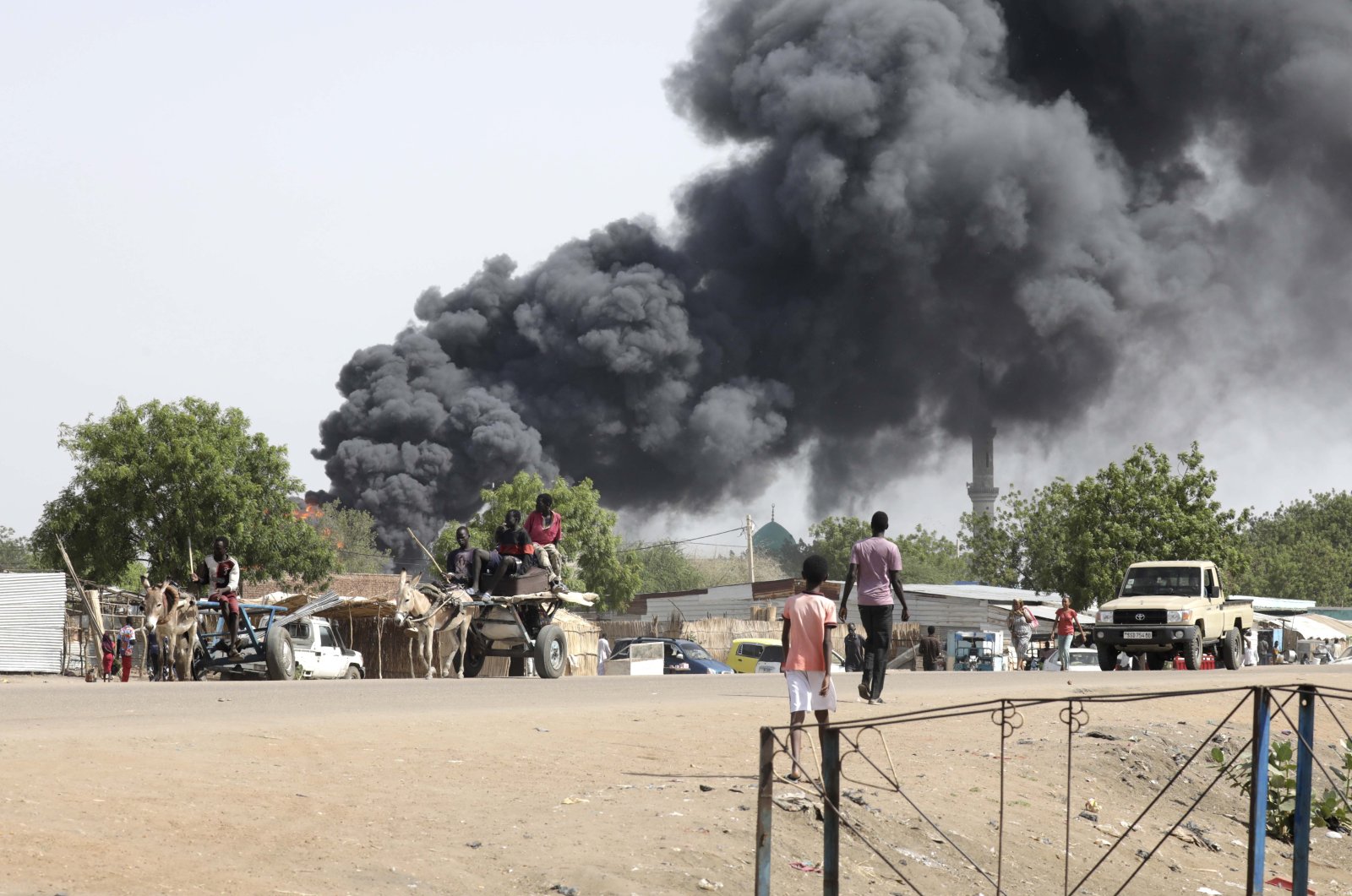 People drive as smoke rises from a fire at a market in the Upper Nile State town of Renk, South Sudan, May 13, 2023. (EPA Photo)