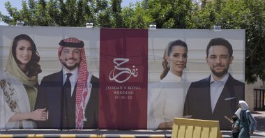 A poster with pictures of Crown Prince Hussein and his fiancee, Saudi architect Rajwa Alseif are displayed near a road in Amman, Jordan, May 31, 2023. (AP Photo)