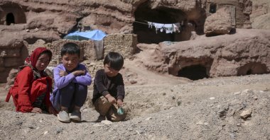 Children pose for a photo in front of their cave homes in Bamyan, central Afghanistan, May 9, 2023. (AA Photo)