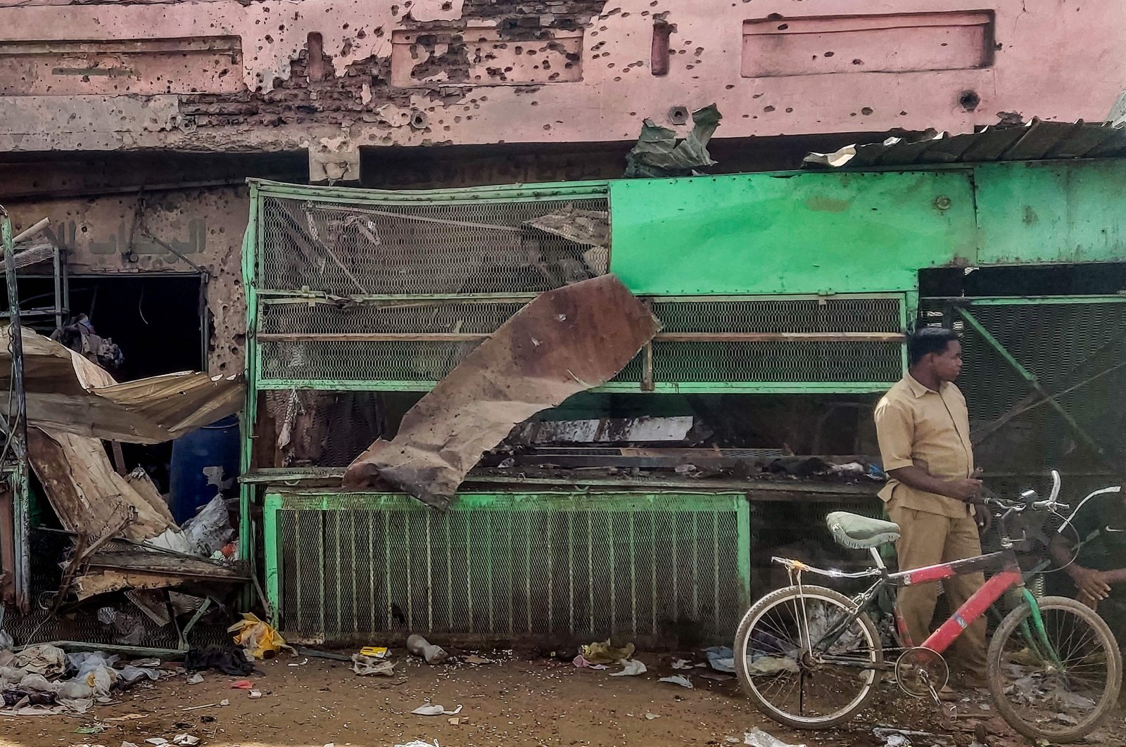 A man stands with a bicycle by a medical centre building riddled with bullet holes at the Souk Sitta or Market Six in Khartoum, Sudan, June 1, 2023. (AFP Photo)