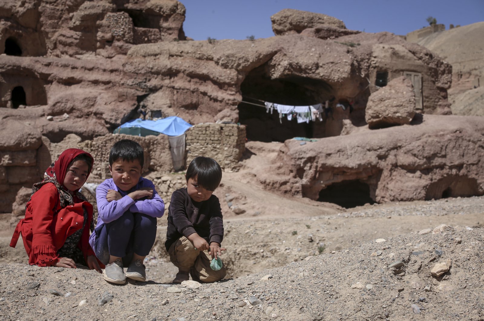 Children pose for a photo in front of their cave homes in Bamyan, central Afghanistan, May 9, 2023. (AA Photo)