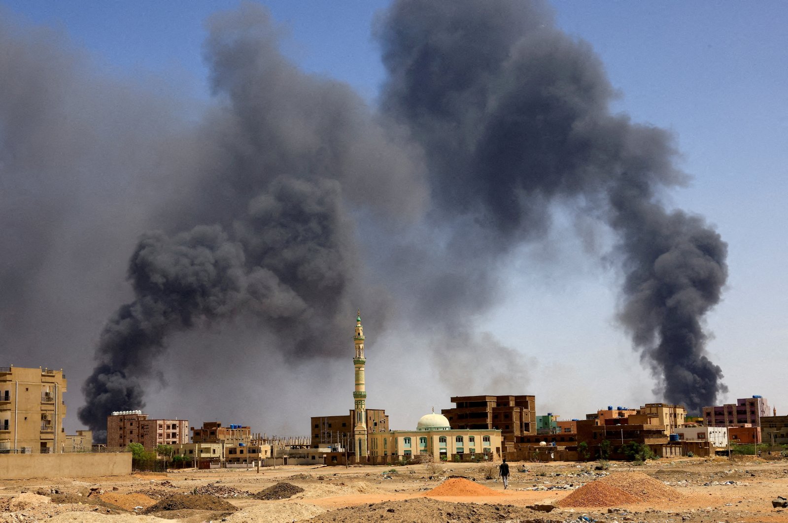 A man walks while smoke rises above buildings after aerial bombardment during clashes in Khartoum, Sudan, May 1, 2023. (Reuters Photo)