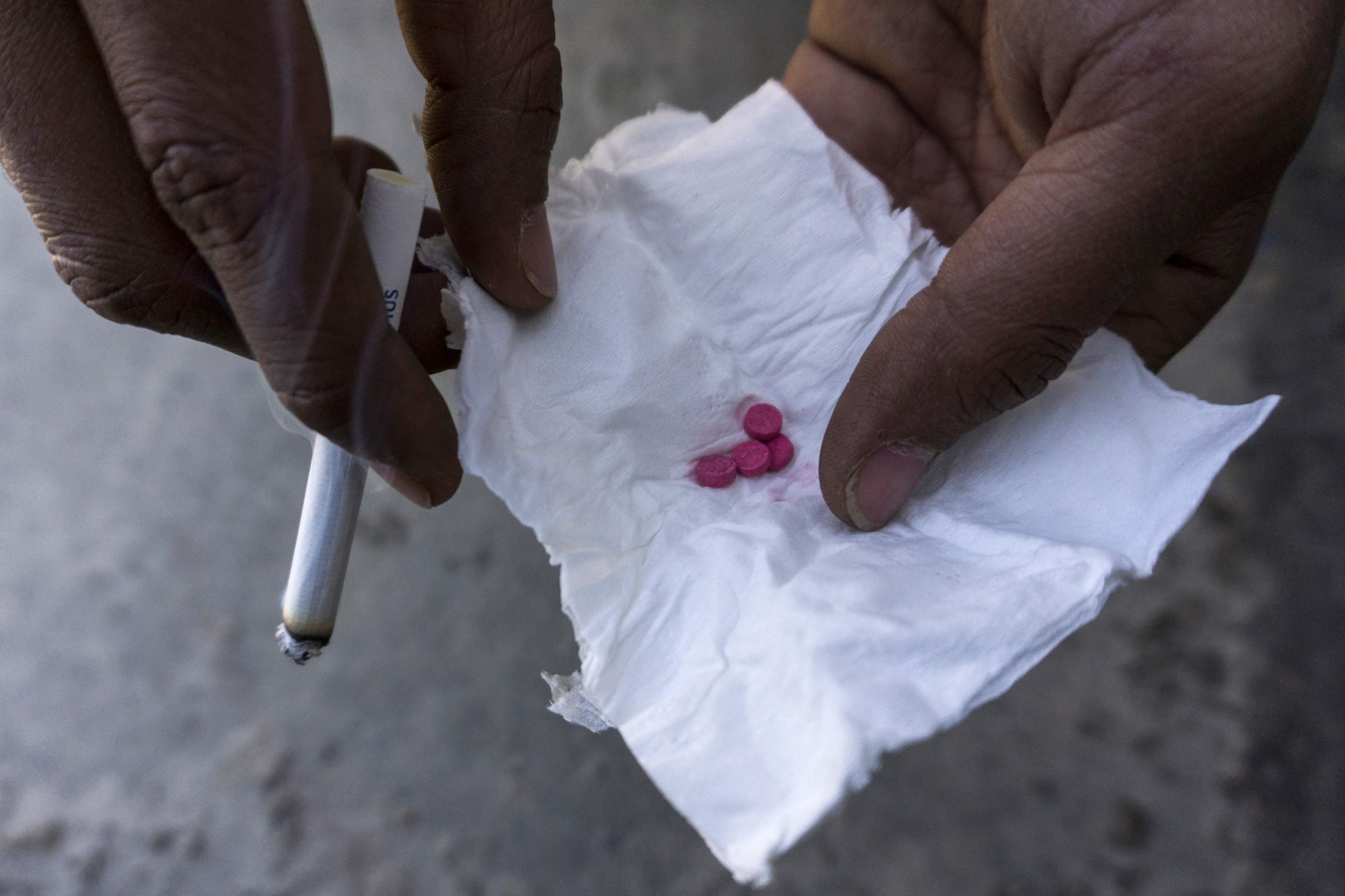 Seorang pengguna narkoba memegang tablet sabu kualitas rendah, yang dikenal di Asia Tenggara sebagai 
