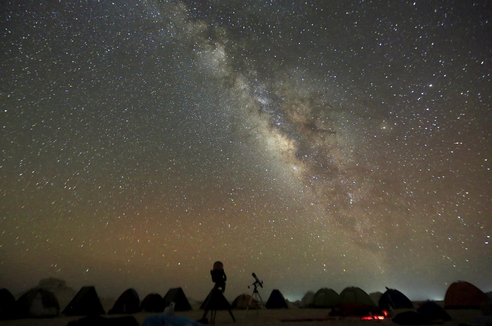 The Milky Way is seen in the night sky around telescopes and camps of people over rocks in the White Desert north of the Farafra Oasis southwest of Cairo, Egypt, May 16, 2015. (Reuters Photo)