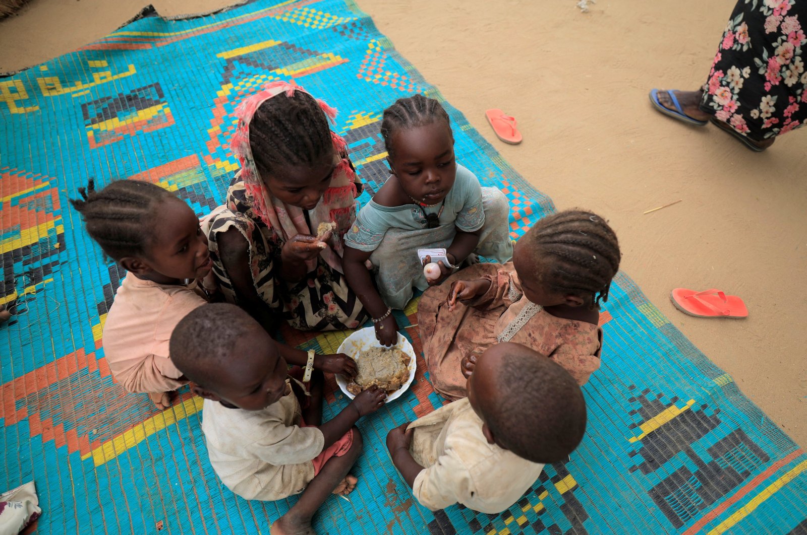 Sudanese refugee children who have fled the violence in Sudan&#039;s Darfur region, eat their breakfast beside makeshift shelters near the border between Sudan and Chad in Koufroun, Chad, May 11, 2023. (Reuters File Photo)