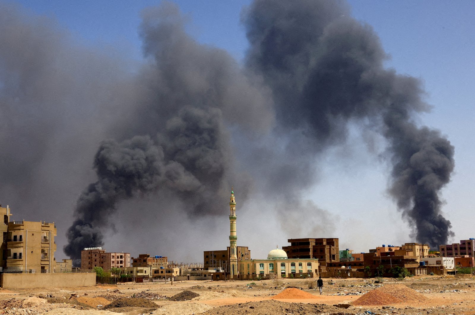 A man walks while smoke rises above buildings after aerial bombardment, during clashes between the paramilitary Rapid Support Forces and the army in Khartoum North, Sudan, May 1, 2023. (Reuters File Photo)