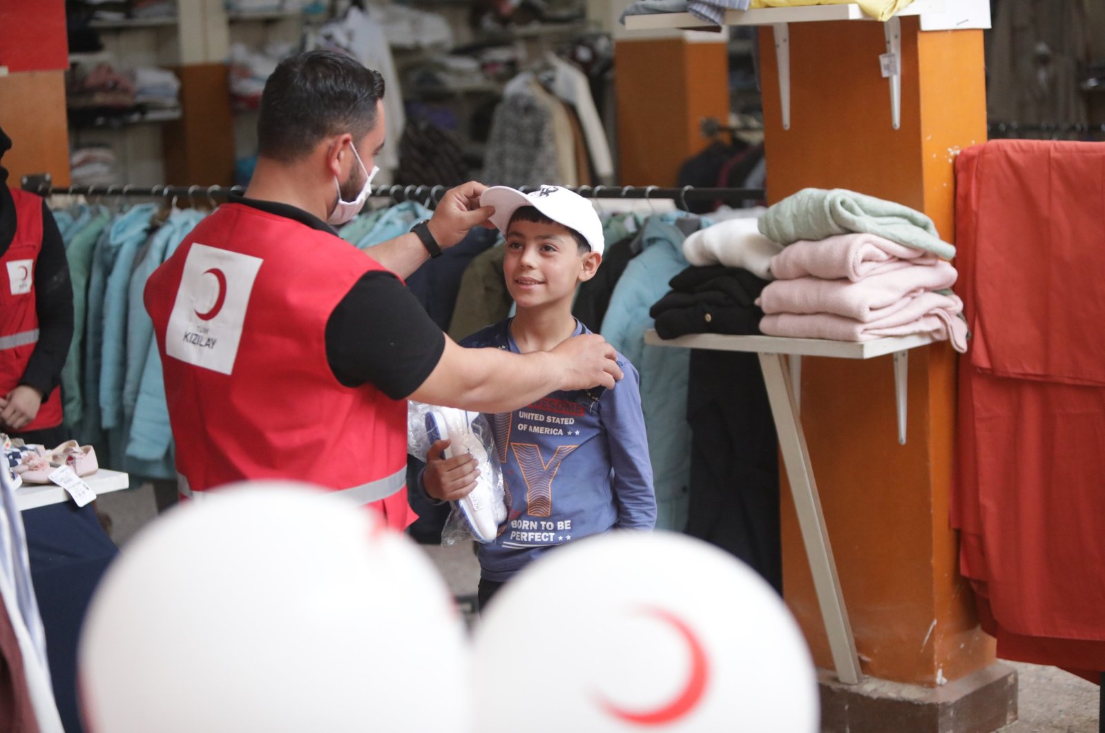 A Turkish Red Crescent worker hands out new clothes to a Syrian boy in Azaz, Syria, July 18, 2021. (AA Photo)