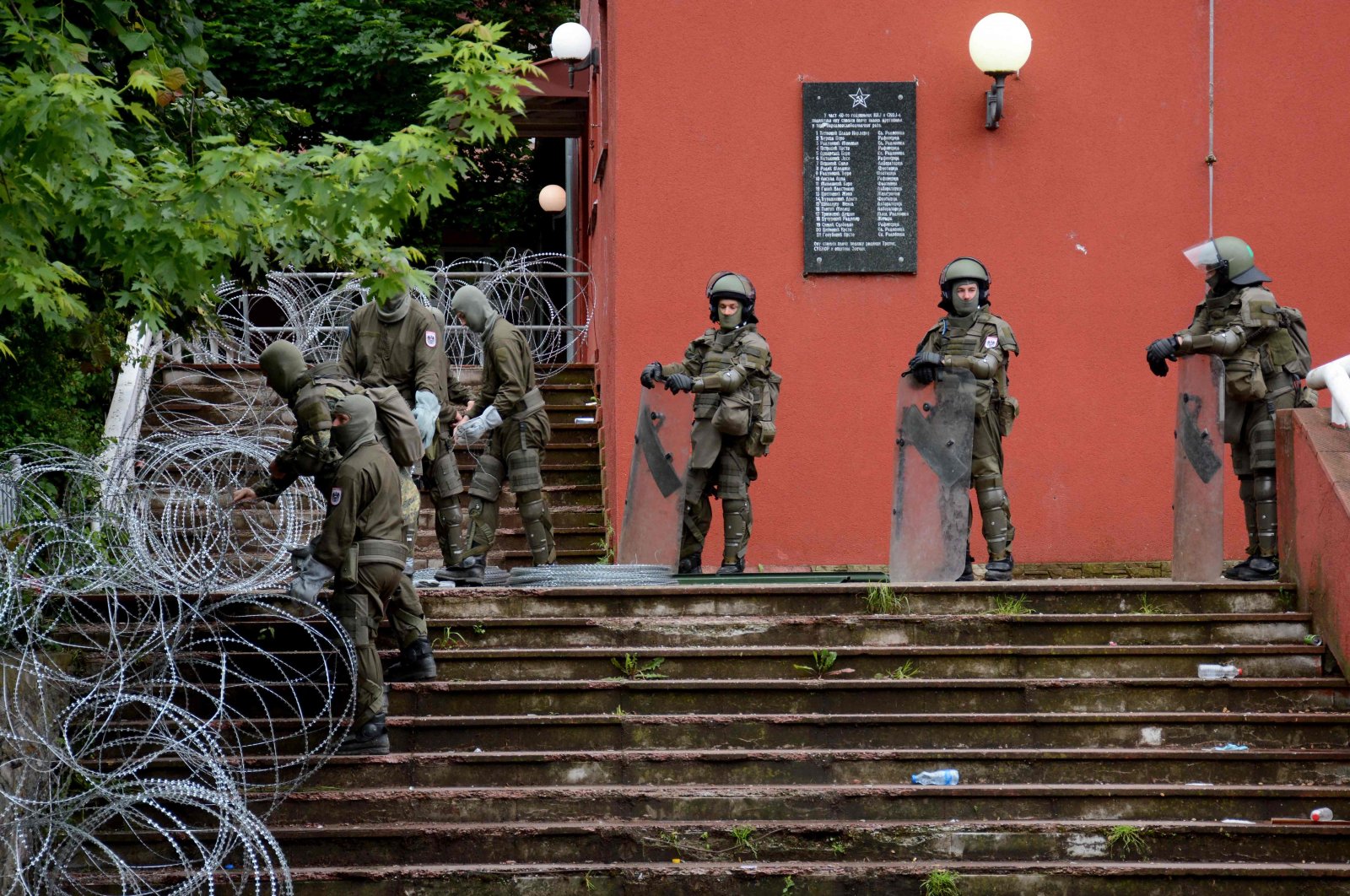 NATO-led Kosovo Force (KFOR) soldiers, wearing full riot gear, place barbed wire around the municipal building in Zvecan following clashes with Serb protesters demanding the removal of recently elected Albanian Mayors, northern Kosovo, May 31, 2023. (AFP Photo)
