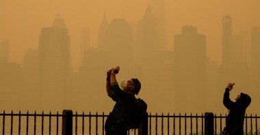 People take photos of the sun as smog causes hazy conditions in New York City, U.S., June 7, 2023. (AFP Photo)