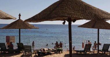 Tourists sunbathe and stand in shallow waters at a closed beach in the Red Sea resort of Sharm el-Sheik, Egypt, Dec. 7, 2010. (AP Photo)