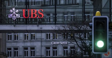 A traffic light signals green in front of the logos of the Swiss banks Credit Suisse and UBS in Zurich, Switzerland, March 19, 2023. (AP Photo)