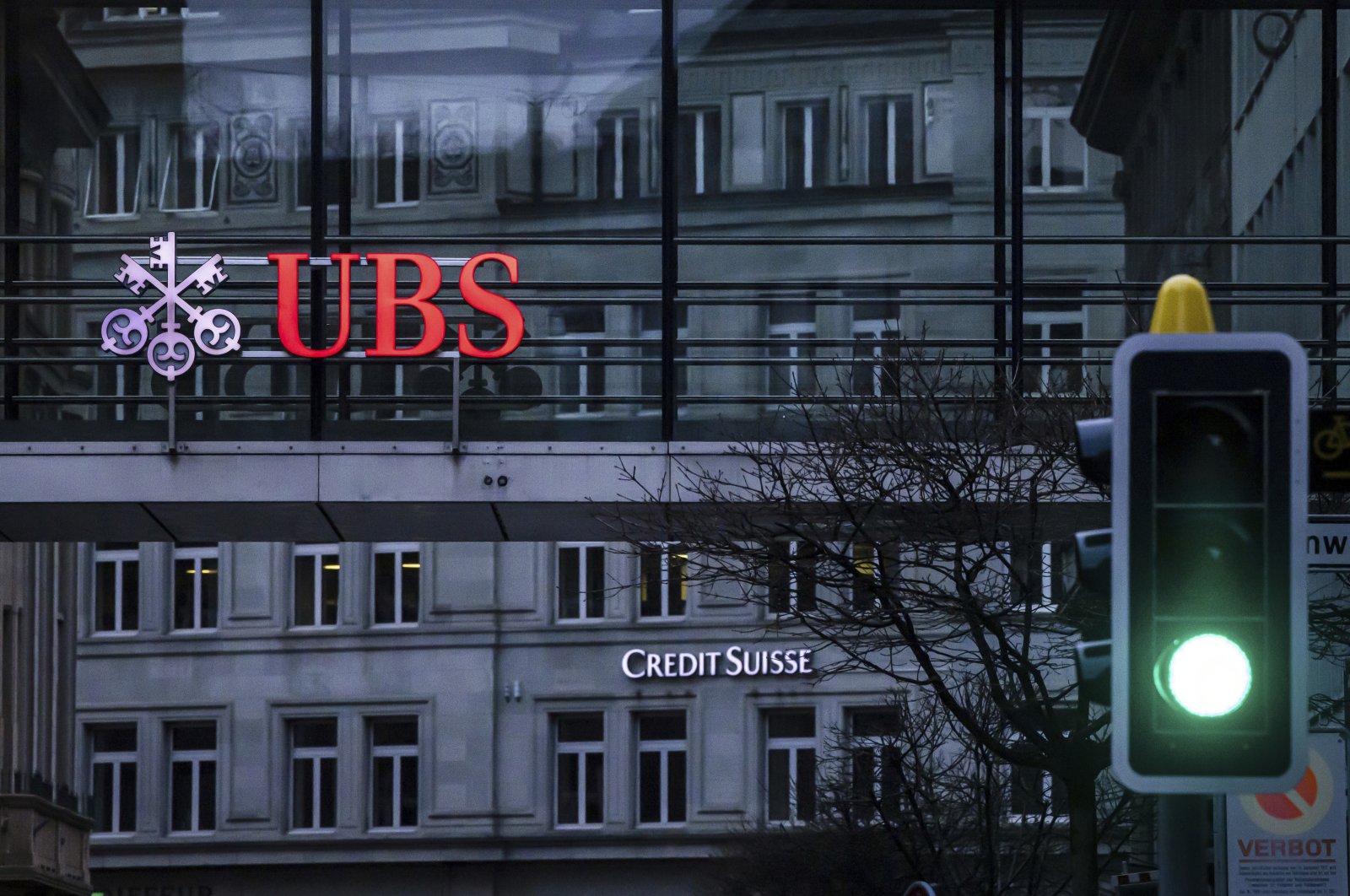 A traffic light signals green in front of the logos of the Swiss banks Credit Suisse and UBS in Zurich, Switzerland, March 19, 2023. (AP Photo)