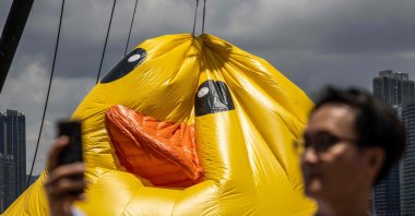 People take photos while one of two large yellow ducks deflate, Victoria Harbour in Hong Kong, China, June 10, 2023. (AFP Photo)