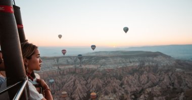 A tourist is seen sighting the fairy chimneys of Cappadocia from a balloon ride, Nevşehir, Türkiye, 2019 (Courtesy Intrepid Travel)