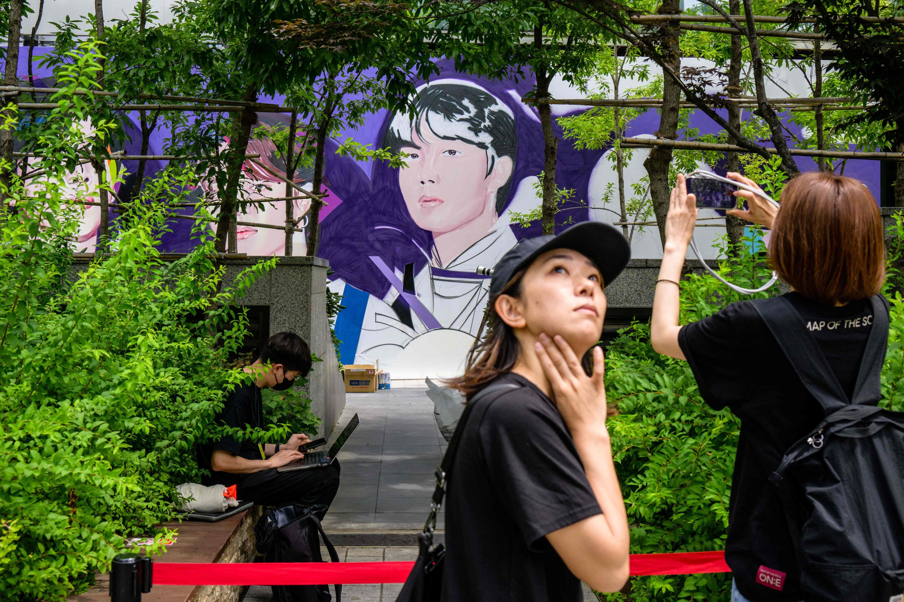 Seorang penggemar mengambil foto mural megabintang K-pop BTS yang sedang dalam pengerjaan di Seoul, Korea Selatan, 12 Juni 2023. (Foto AFP)