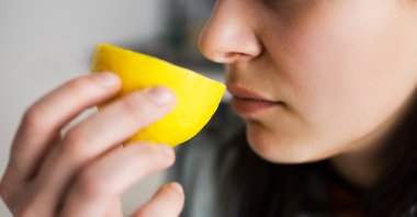 A woman suffering from COVID-19 smells a lemon. (Shutterstock Photo)