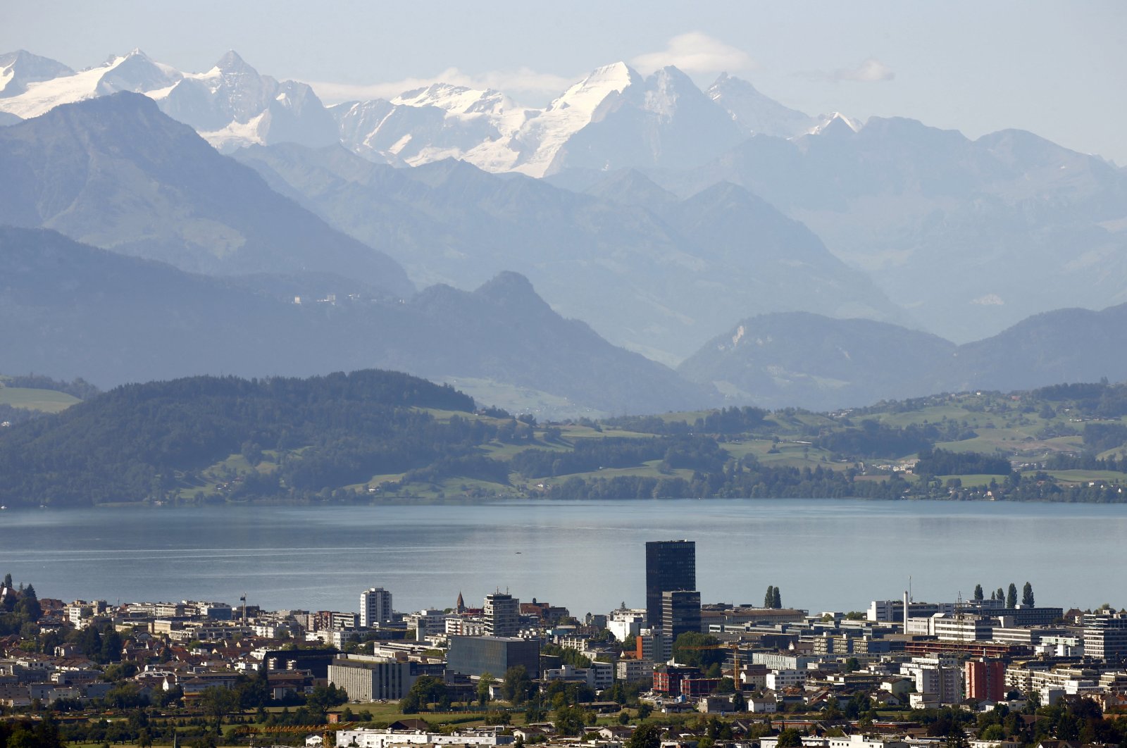 The snow-covered peaks of Bernese Oberland are seen behind Lake Zug and the city of Zug, Switzerland, Aug. 20, 2020. (Reuters Photo)