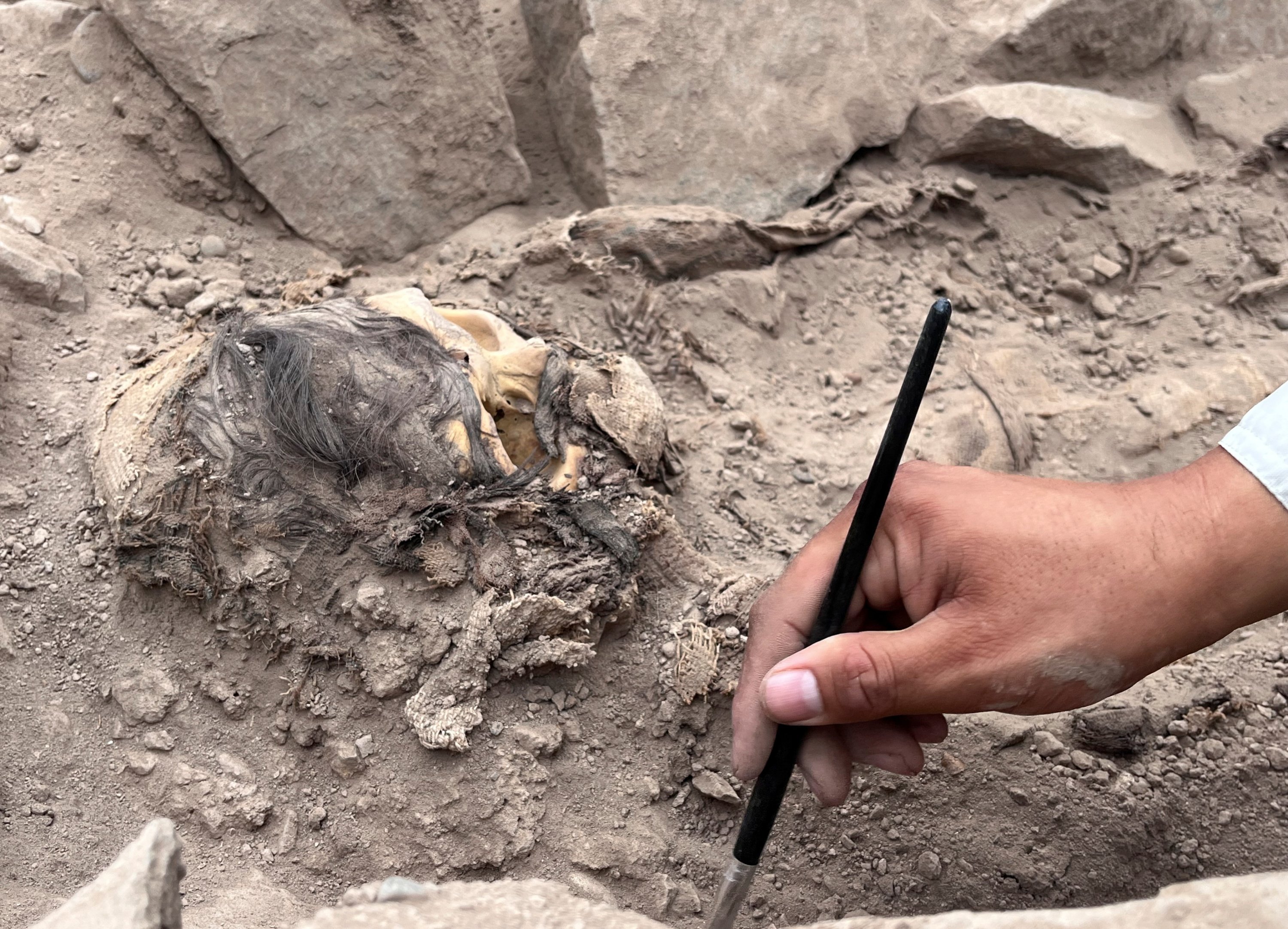 Seorang arkeolog bekerja di situs penggalian pemakaman pra-Hispanik di samping mumi yang diyakini berasal dari budaya Manchay, yang berkembang di lembah Lima antara 1.500 dan 1.000 SM, Lima, Peru, 14 Juni 2023. (Foto Reuters )