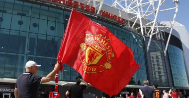 A flag seller waves a Manchester United flag as fans arrive for the English Premier League soccer match between Manchester United and Crystal Palace outside Old Trafford in Manchester, England, Aug., 24, 2019. (AP Photo)