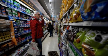 Adrian Alvarez, 63, instructor of transcendental meditation, checks prices at the supermarket in Buenos Aires on June 12, 2023. (Photo by Luis ROBAYO / AFP)