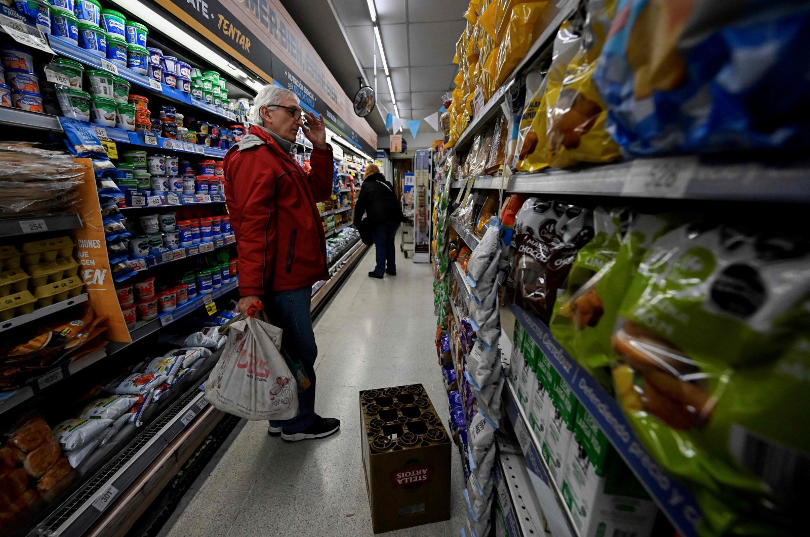 Adrian Alvarez, 63, instructor of transcendental meditation, checks prices at the supermarket in Buenos Aires on June 12, 2023. (Photo by Luis ROBAYO / AFP)