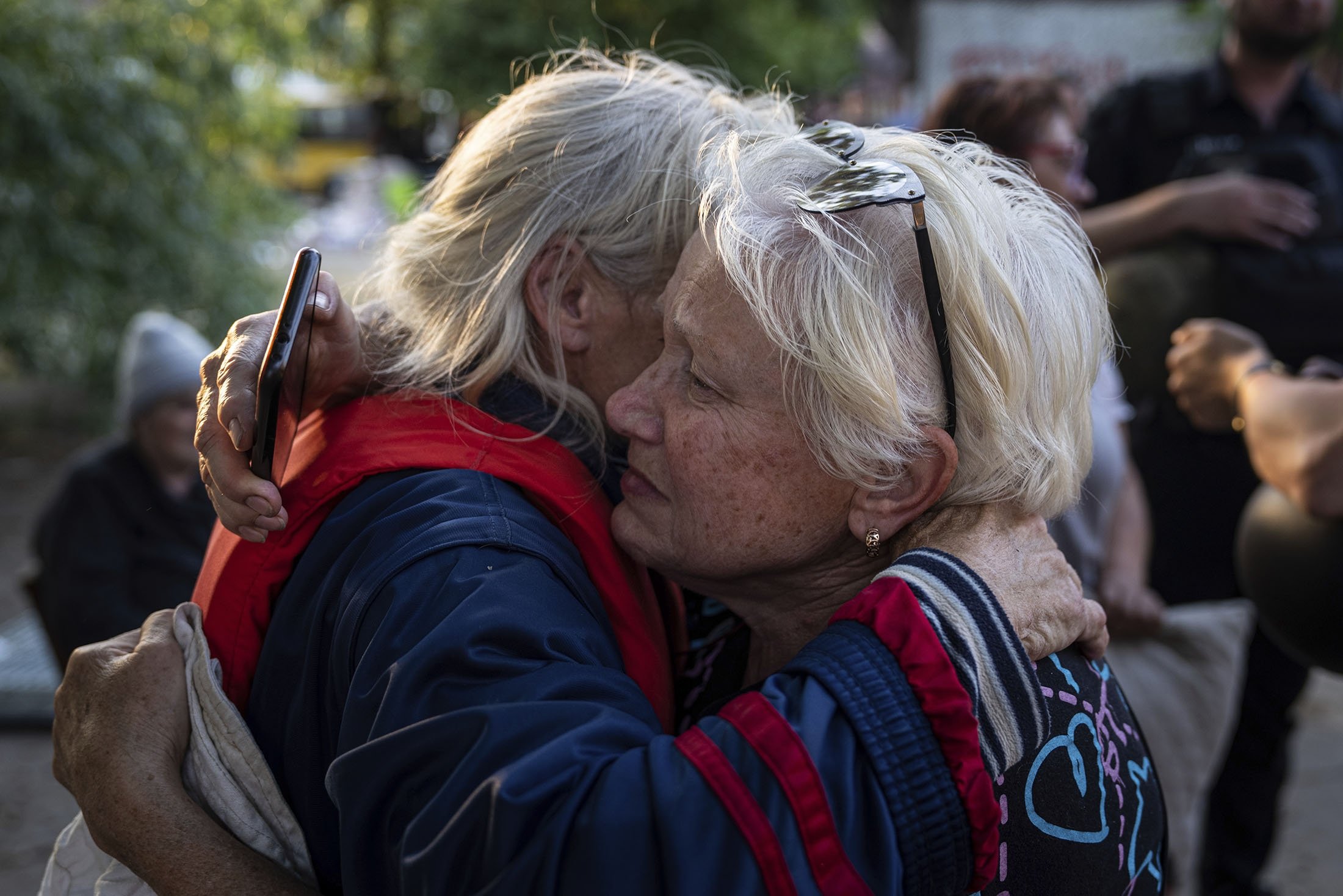 Tetyana, kanan, memeluk tetangganya Hanna setelah dievakuasi dari desa Kardashynka yang dilanda banjir di tepi kiri sungai Dnipro, di Kherson, Ukraina, 9 Juni 2023. (Foto AP)