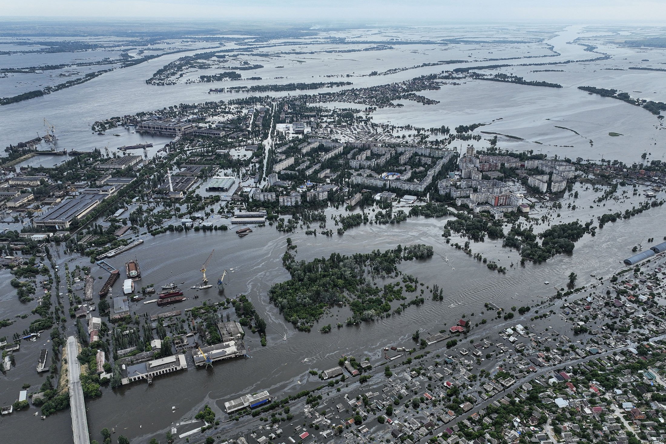 Rumah-rumah terlihat di bawah air dan tercemar oleh minyak di lingkungan yang terendam banjir, di Kherson, Ukraina, 10 Juni 2023. (Foto AP)