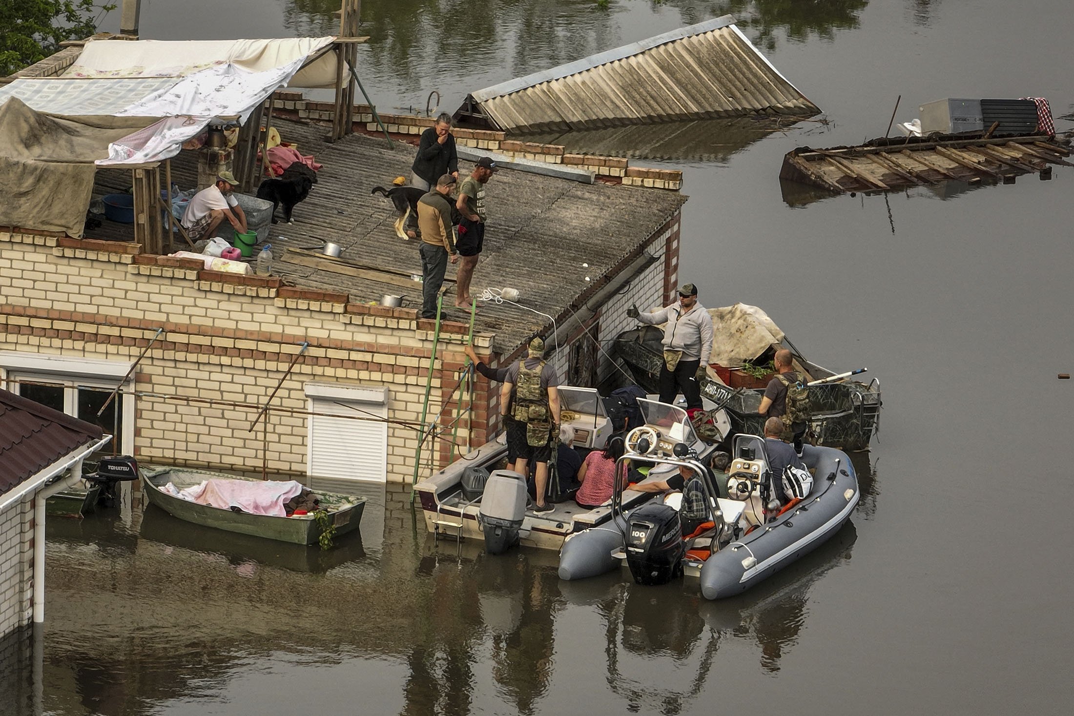 Prajurit Ukraina membantu warga turun dari atap ke perahu penyelamat selama evakuasi di lingkungan banjir dekat Oleshky, Ukraina, 7 Juni 2023. (Foto AP)