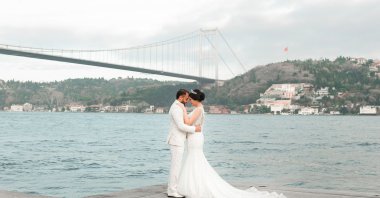 A newlywed couple poses with the Bosporus in the background, in Istanbul, Türkiye, Feb. 20, 2021. (Shutterstock Photo)