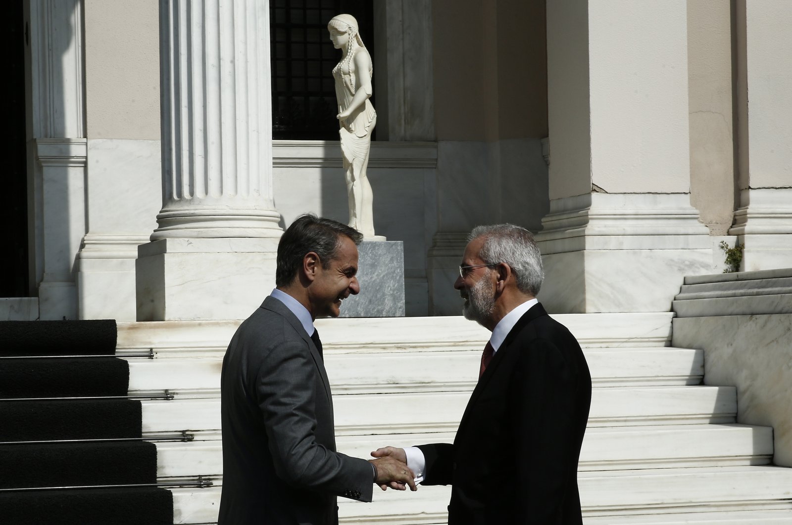 Greek Former Prime Minister Kyriakos Mitsotakis (L) shakes hands with new caretaker Prime Minister Ioannis Sarmas (R) during the handover ceremony at Maximos Mansion in Athens, Greece, 25 May 2023. (EPA Photo)